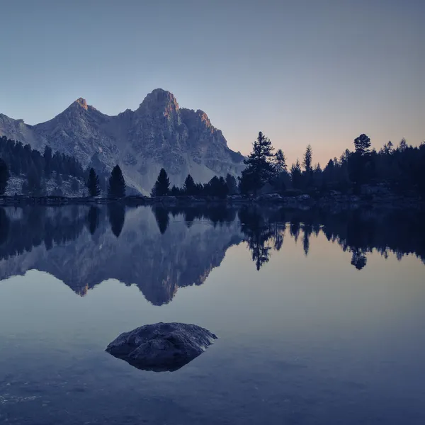 A winding mountain road with sharp hairpin turns leading toward the jagged peaks of the Sella Group